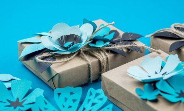 Hediye kutusu craft kağıt mavi arka planda sarılmış. Sakura çiçek kağıt origami yaptı. Hediye.