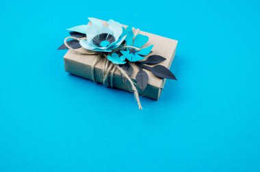Hediye kutusu craft kağıt mavi arka planda sarılmış. Sakura çiçek kağıt origami yaptı. Hediye.