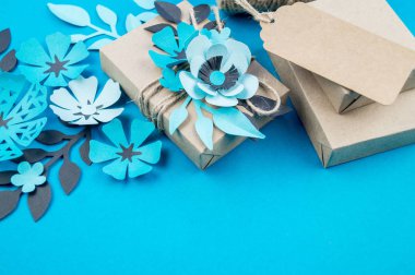 Hediye kutusu craft kağıt mavi arka planda sarılmış. Sakura çiçek kağıt origami yaptı. Hediye.