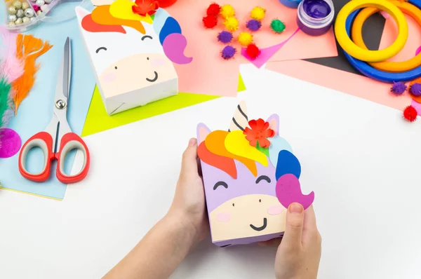 A box with a gift inside in the form of a rainbow unicorn. Children\'s paper craft school kindergarten. Party with a surprise.