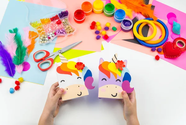 A box with a gift inside in the form of a rainbow unicorn. Children\'s paper craft school kindergarten. Party with a surprise.