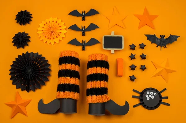 Orange background with collection of Halloween objects overhead view. Black cat, spider, bat, witch, feared party decor. Handwork.