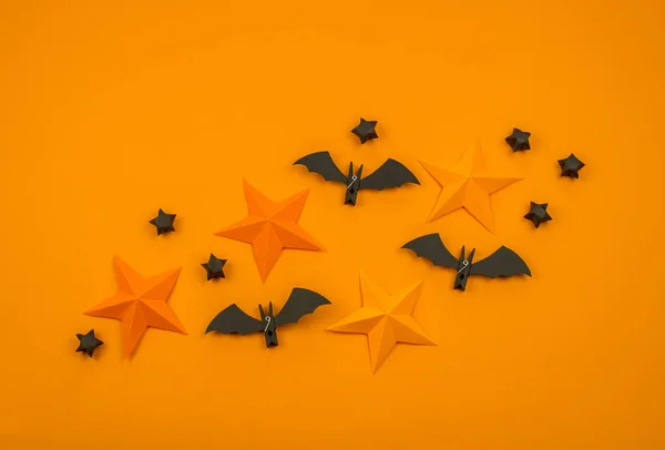 Orange background with collection of Halloween objects overhead view. Spider, bat, stars, holiday pattern.