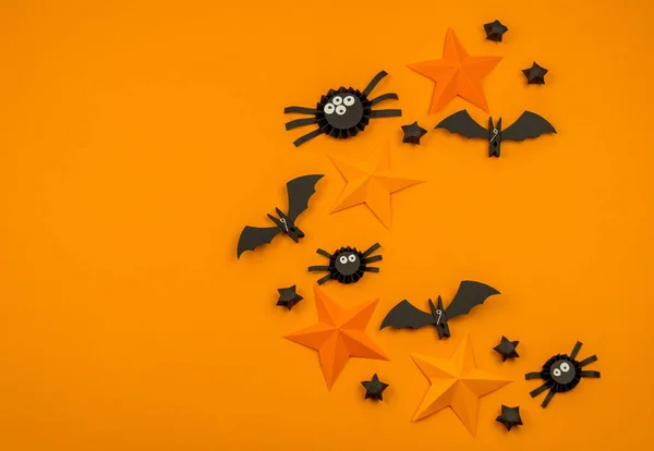 Orange background with collection of Halloween objects overhead view. Spider, bat, stars, holiday pattern.