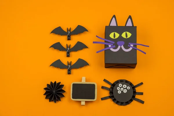Orange background with collection of Halloween objects overhead view. Black cat, spider, bat, witch, feared party decor. Handwork.