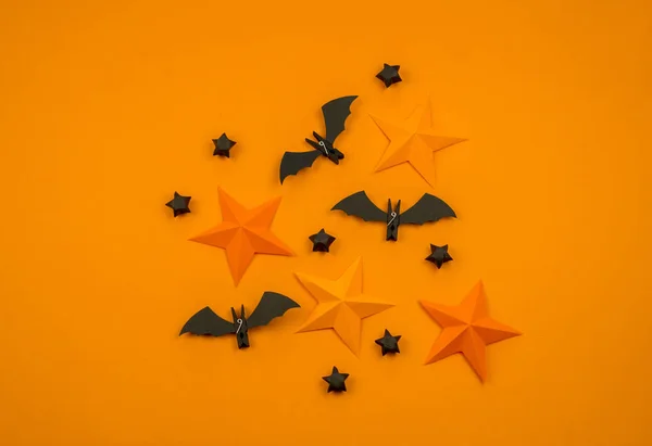 Orange background with collection of Halloween objects overhead view. Spider, bat, stars, holiday pattern.