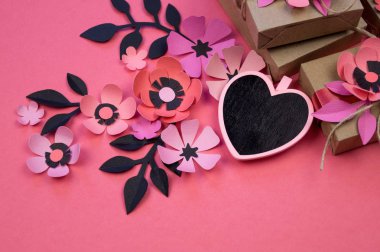 Vintage hediye kutuları Eko kağıt üzerinde pembe bir arka plan. Hediye gül çiçek sakura ve yaprakları ile süslenmiş. Siyah kalp yazmak için. Sevgililer günü veya diğer tatil kavramı, üstten görünüm, düz yatıyordu, havai görünümü