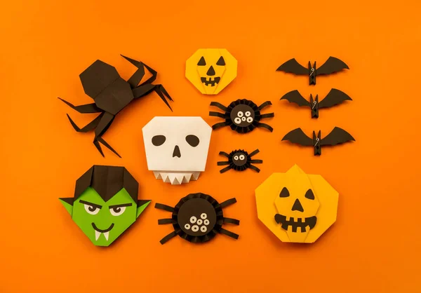 Orange background with collection of Halloween objects overhead view. Skull, pumpkin, ghost, monster, green hand, spider, bat, witch, feared party decor. Handwork.