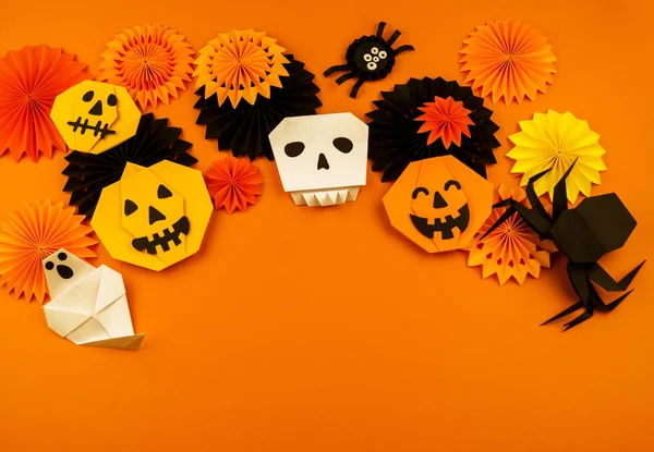 Orange background with collection of Halloween objects overhead view. Skull, pumpkin, ghost, monster, green hand, spider, bat, witch, feared party decor. Handwork.