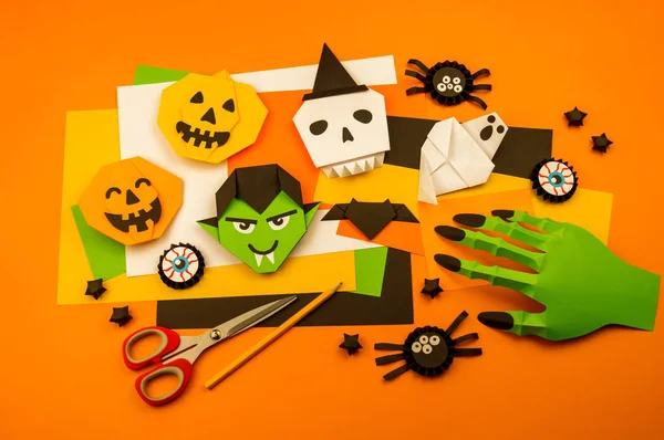 Orange background with collection of Halloween objects overhead view. Skull, pumpkin, ghost, monster, green hand, spider, bat, witch, feared party decor. Handwork.