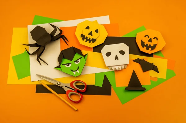 Orange background with collection of Halloween objects overhead view. Skull, pumpkin, ghost, monster, green hand, spider, bat, witch, feared party decor. Handwork.