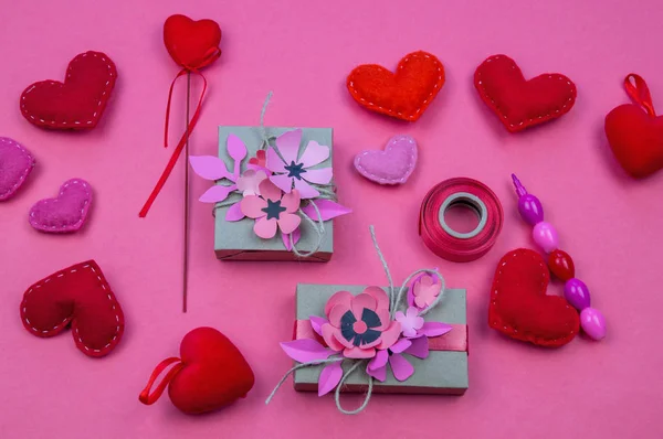 Gift boxes wrapped in red checked paper and the contents of a workspace composed. Different objects on a pink color table. Flat lay.Holiday decor concept.