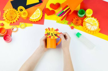 Çocuk kağıt zanaat aslan atölye yapıyor. Sıcak Afrika'dan bir hayvan. Çocuk eli. Yaratıcılık için malzeme. Beyaz arka plan.