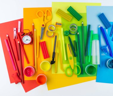 Okul aksesuarları bir gökkuşağı şeklinde yerleştirilir. Beyaz arka plan. Geri okul öğrenci için çok mutluyum. Sanat ve el sanatları çocuklar için. Gökkuşağı renkleri, alfabe harfler ve sayılar öğrenme çocuk.