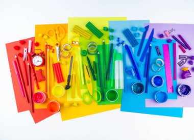 Okul aksesuarları bir gökkuşağı şeklinde yerleştirilir. Beyaz arka plan. Geri okul öğrenci için çok mutluyum. Sanat ve el sanatları çocuklar için. Gökkuşağı renkleri, alfabe harfler ve sayılar öğrenme çocuk.