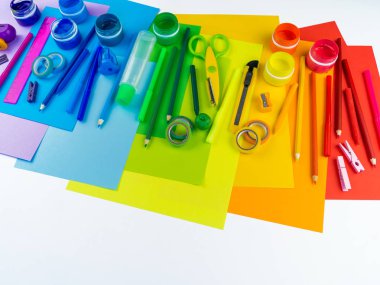 Okul aksesuarları bir gökkuşağı şeklinde yerleştirilir. Beyaz arka plan. Geri okul öğrenci için çok mutluyum. Sanat ve el sanatları çocuklar için. Gökkuşağı renkleri, alfabe harfler ve sayılar öğrenme çocuk.