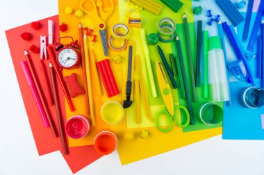 Okul aksesuarları bir gökkuşağı şeklinde yerleştirilir. Beyaz arka plan. Geri okul öğrenci için çok mutluyum. Sanat ve el sanatları çocuklar için. Gökkuşağı renkleri, alfabe harfler ve sayılar öğrenme çocuk.