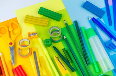 Okul aksesuarları bir gökkuşağı şeklinde yerleştirilir. Beyaz arka plan. Geri okul öğrenci için çok mutluyum. Sanat ve el sanatları çocuklar için. Gökkuşağı renkleri, alfabe harfler ve sayılar öğrenme çocuk.