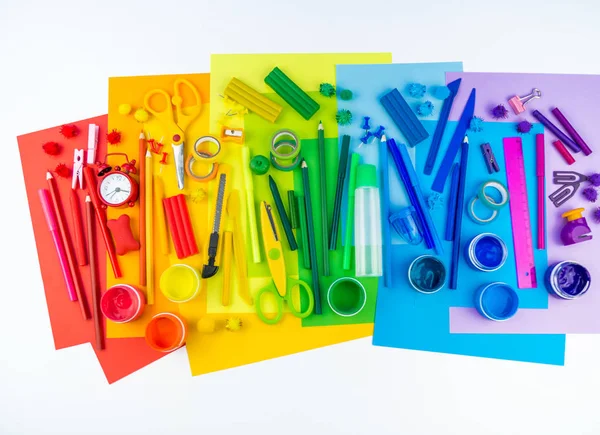 Okul aksesuarları bir gökkuşağı şeklinde yerleştirilir. Beyaz arka plan. Geri okul öğrenci için çok mutluyum. Sanat ve el sanatları çocuklar için. Gökkuşağı renkleri, alfabe harfler ve sayılar öğrenme çocuk.