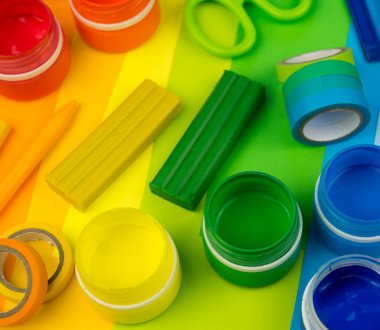 Okul aksesuarları gökkuşağı şeklinde ortaya konur. Siyah arka plan. Okul öğrencisine mutlu. Çocuklar için sanat ve el sanatları. Gökkuşağı renkleri, alfabe harfleri ve sayıları öğrenen çocuk.