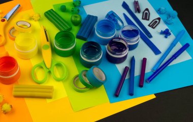 Okul aksesuarları gökkuşağı şeklinde ortaya konur. Siyah arka plan. Okul öğrencisine mutlu. Çocuklar için sanat ve el sanatları. Gökkuşağı renkleri, alfabe harfleri ve sayıları öğrenen çocuk.