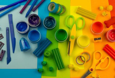 Okul aksesuarları gökkuşağı şeklinde ortaya konur. Siyah arka plan. Okul öğrencisine mutlu. Çocuklar için sanat ve el sanatları. Gökkuşağı renkleri, alfabe harfleri ve sayıları öğrenen çocuk.