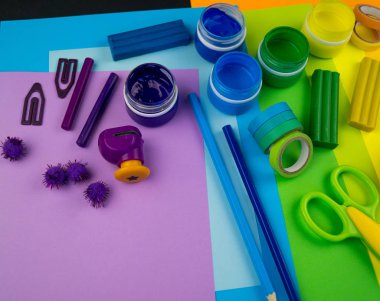 Okul aksesuarları gökkuşağı şeklinde ortaya konur. Siyah arka plan. Okul öğrencisine mutlu. Çocuklar için sanat ve el sanatları. Gökkuşağı renkleri, alfabe harfleri ve sayıları öğrenen çocuk.