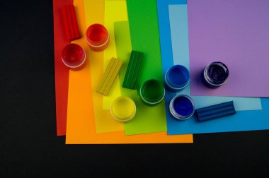 Okul aksesuarları gökkuşağı şeklinde ortaya konur. Siyah arka plan. Okul öğrencisine mutlu. Çocuklar için sanat ve el sanatları. Gökkuşağı renkleri, alfabe harfleri ve sayıları öğrenen çocuk.