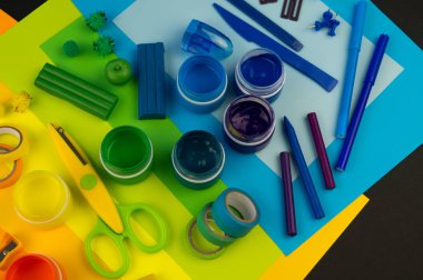 Okul aksesuarları gökkuşağı şeklinde ortaya konur. Siyah arka plan. Okul öğrencisine mutlu. Çocuklar için sanat ve el sanatları. Gökkuşağı renkleri, alfabe harfleri ve sayıları öğrenen çocuk.