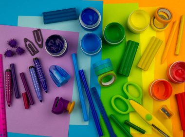 Okul aksesuarları gökkuşağı şeklinde ortaya konur. Siyah arka plan. Okul öğrencisine mutlu. Çocuklar için sanat ve el sanatları. Gökkuşağı renkleri, alfabe harfleri ve sayıları öğrenen çocuk.