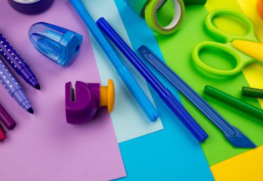 Okul aksesuarları gökkuşağı şeklinde ortaya konur. Siyah arka plan. Okul öğrencisine mutlu. Çocuklar için sanat ve el sanatları. Gökkuşağı renkleri, alfabe harfleri ve sayıları öğrenen çocuk.