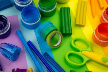 Okul aksesuarları gökkuşağı şeklinde ortaya konur. Siyah arka plan. Okul öğrencisine mutlu. Çocuklar için sanat ve el sanatları. Gökkuşağı renkleri, alfabe harfleri ve sayıları öğrenen çocuk.