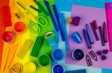 Okul aksesuarları gökkuşağı şeklinde ortaya konur. Siyah arka plan. Okul öğrencisine mutlu. Çocuklar için sanat ve el sanatları. Gökkuşağı renkleri, alfabe harfleri ve sayıları öğrenen çocuk.