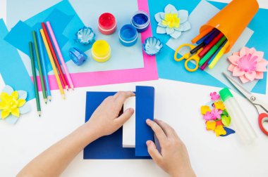 Çocuk elleri kağıttan penguen yapıyor. Çocukların yaratıcılığının uygulanması. Anaokulu ve zanaat okulu. Beyaz arka plan ve el sanatları için malzemeler.