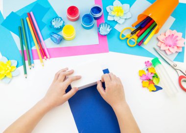 Çocuk elleri kağıttan penguen yapıyor. Çocukların yaratıcılığının uygulanması. Anaokulu ve zanaat okulu. Beyaz arka plan ve el sanatları için malzemeler.