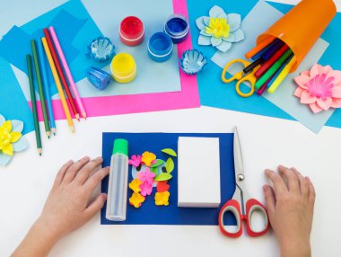 Çocuk elleri kağıttan penguen yapıyor. Çocukların yaratıcılığının uygulanması. Anaokulu ve zanaat okulu. Beyaz arka plan ve el sanatları için malzemeler.