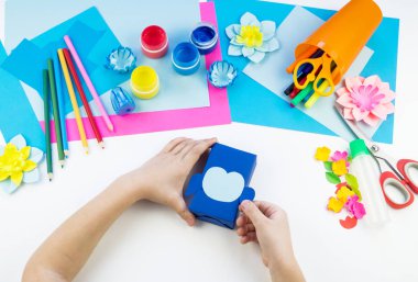 Çocuk elleri kağıttan penguen yapıyor. Çocukların yaratıcılığının uygulanması. Anaokulu ve zanaat okulu. Beyaz arka plan ve el sanatları için malzemeler.