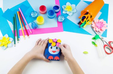 Çocuk elleri kağıttan penguen yapıyor. Çocukların yaratıcılığının uygulanması. Anaokulu ve zanaat okulu. Beyaz arka plan ve el sanatları için malzemeler.