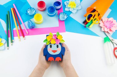 Çocuk elleri kağıttan penguen yapıyor. Çocukların yaratıcılığının uygulanması. Anaokulu ve zanaat okulu. Beyaz arka plan ve el sanatları için malzemeler.