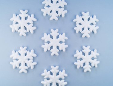 Mavi bir arka plan üzerinde dekoratif kar taneleri deseni. Festival süsleme. Strafor yumuşak pastel renk