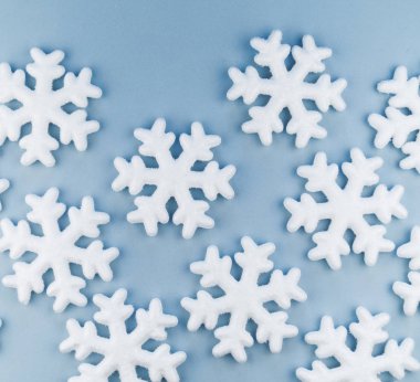 Mavi bir arka plan üzerinde dekoratif kar taneleri deseni. Festival süsleme. Strafor yumuşak pastel renk