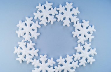 Mavi bir arka plan üzerinde dekoratif kar taneleri bir daire içinde bir çelenk. Köpük. Yumuşak pastel renk