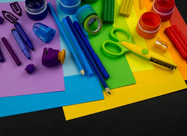 School accessories are laid out in the form of a rainbow. Black background.Happy back to school student. Art and crafts for kids. Child learning rainbow colors, alphabet letters and numbers.