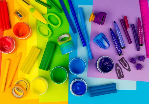 Okul aksesuarları gökkuşağı şeklinde ortaya konur. Siyah arka plan. Okul öğrencisine mutlu. Çocuklar için sanat ve el sanatları. Gökkuşağı renkleri, alfabe harfleri ve sayıları öğrenen çocuk.