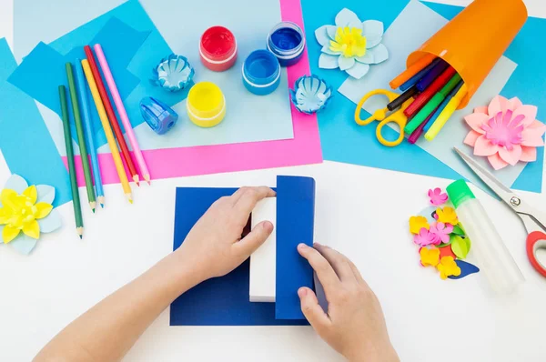 Çocuk elleri kağıttan penguen yapıyor. Çocukların yaratıcılığının uygulanması. Anaokulu ve zanaat okulu. Beyaz arka plan ve el sanatları için malzemeler.