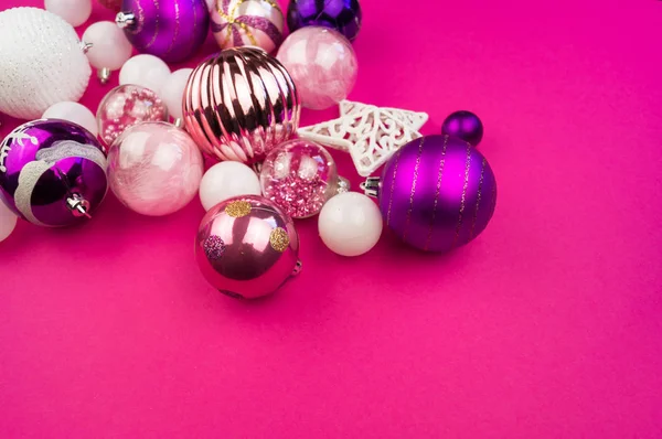 Gentle pink and purple baubles on a pink background. Christmas mood. Festive decor. Sequins and glitter for a party.