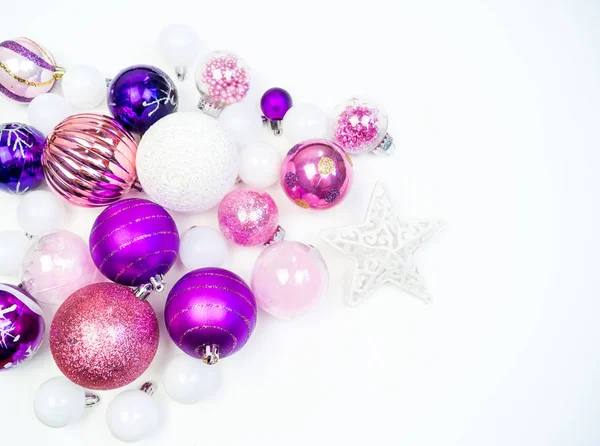 Gentle pink and purple baubles on a white background. Christmas mood. Festive decor. Sequins and glitter for a party.