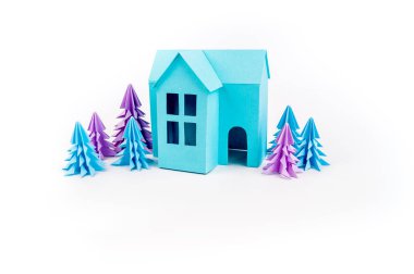 Mavi Ev kağıdımız yapıştırılmış menekşe ormanda duruyor. Beyaz arka plan. Çocuk el sanatları. Noel ağacı.