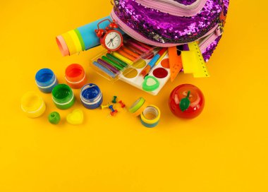 İleti örneği öğeleri sarı bir arka plan üzerinde bir sırt çantası. Mor kız çanta pullu Parlatıcı ile. Okula dönüş. Gökkuşağı rengi. Anaokulu yaratıcılık.