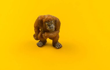 Sarı bir arka plan üzerinde plastik oyuncak orangutan. Hayvanlarıyla bir çocuk için. Yazmak için bir yer.